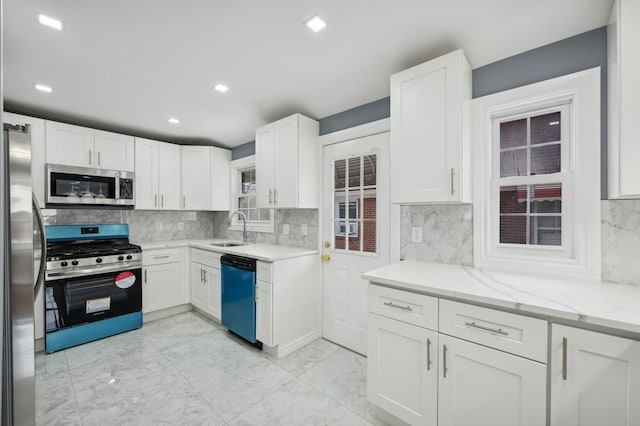 kitchen featuring white cabinets, stainless steel appliances, light stone counters, and sink