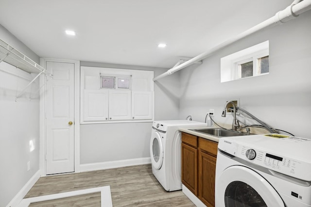 laundry room featuring cabinets, washing machine and dryer, light hardwood / wood-style floors, and sink