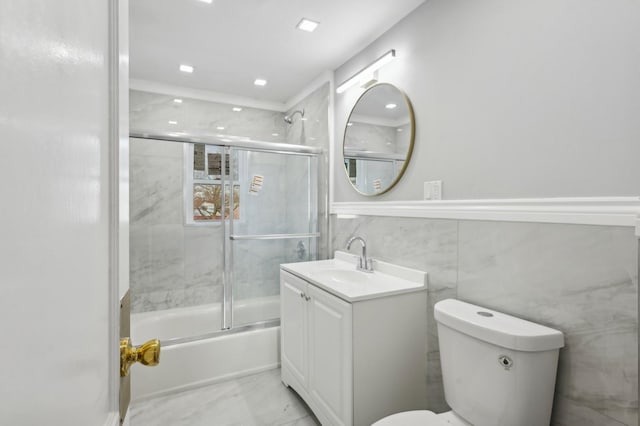 full bathroom with shower / bath combination with glass door, vanity, tile walls, and toilet