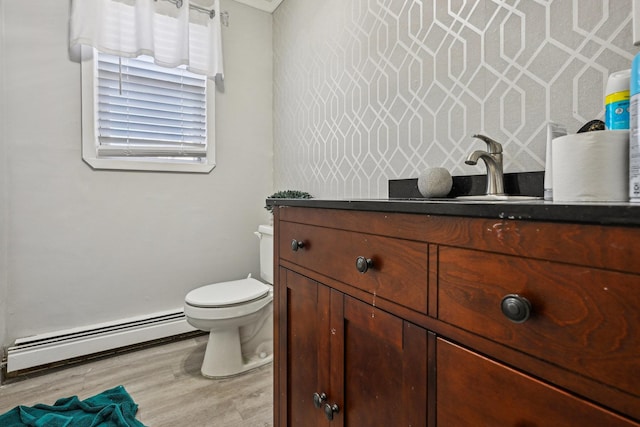 bathroom with hardwood / wood-style floors, vanity, toilet, and a baseboard heating unit