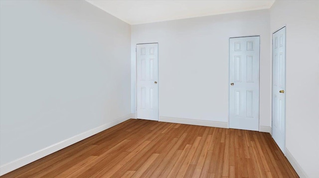 unfurnished bedroom featuring light hardwood / wood-style floors and multiple closets