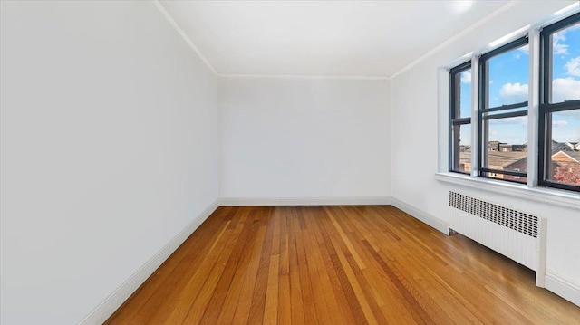 spare room with light wood-type flooring, ornamental molding, and radiator