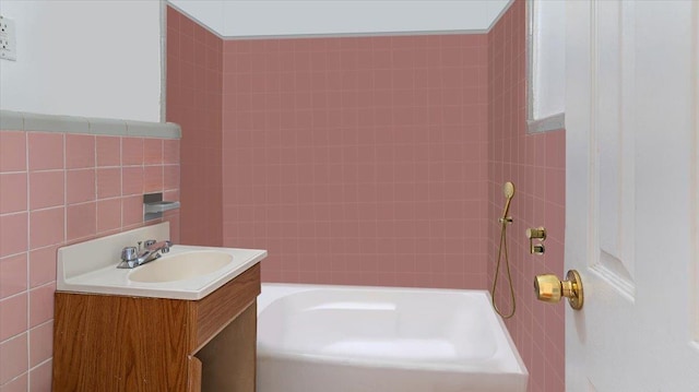 bathroom featuring a bathtub, tile walls, and vanity