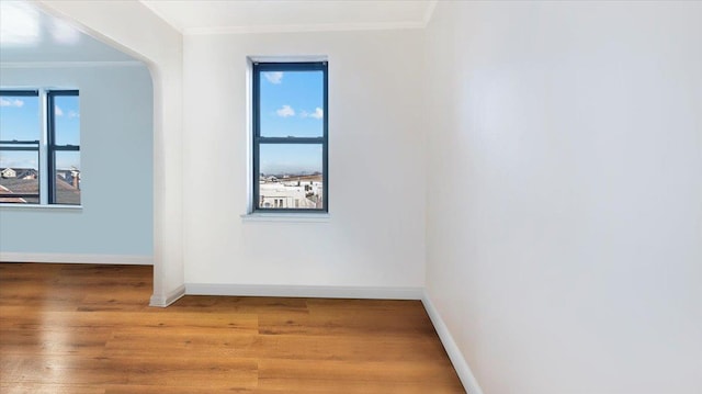 spare room featuring ornamental molding, hardwood / wood-style flooring, and a healthy amount of sunlight