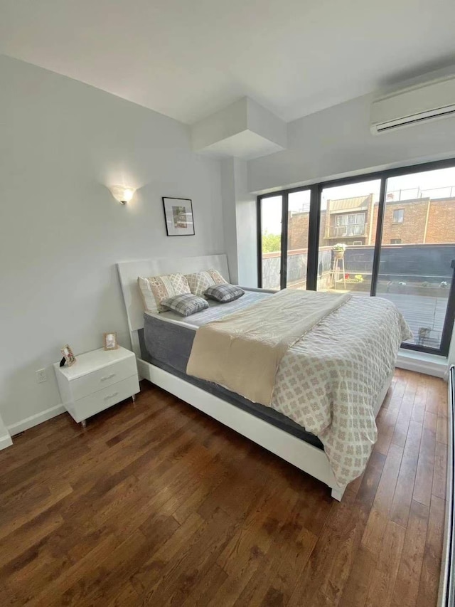 bedroom with an AC wall unit and dark wood-type flooring