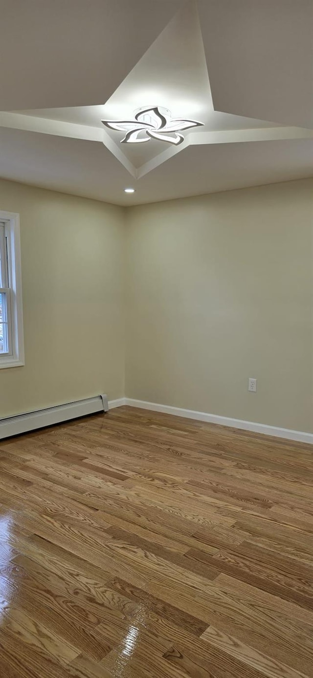 spare room with hardwood / wood-style floors and a baseboard heating unit