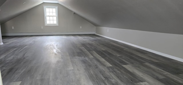 additional living space featuring dark hardwood / wood-style floors, vaulted ceiling, and a baseboard heating unit