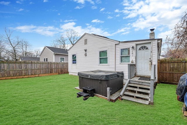 rear view of property featuring a yard and a hot tub