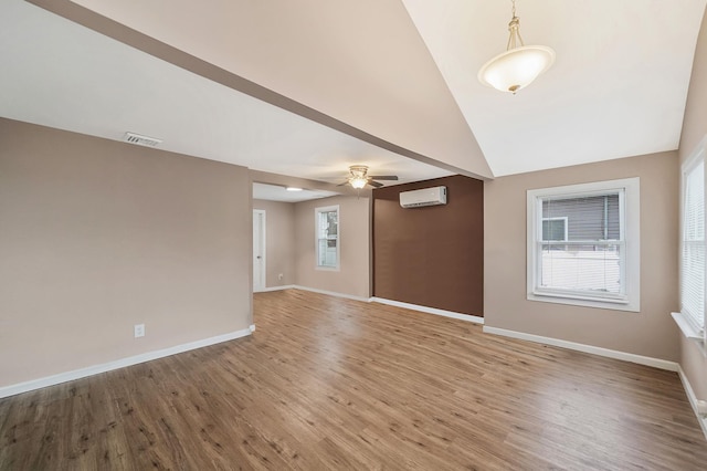 spare room with an AC wall unit, ceiling fan, vaulted ceiling, and hardwood / wood-style flooring