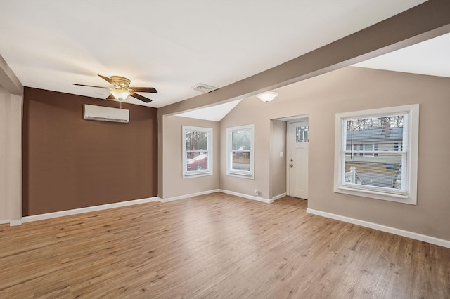 spare room featuring vaulted ceiling with beams, light hardwood / wood-style floors, a wall unit AC, and plenty of natural light