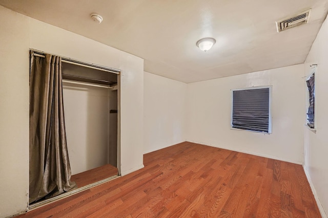 unfurnished bedroom featuring wood-type flooring and a closet