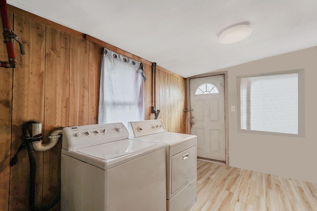 laundry room with washer and dryer, light hardwood / wood-style flooring, and wooden walls