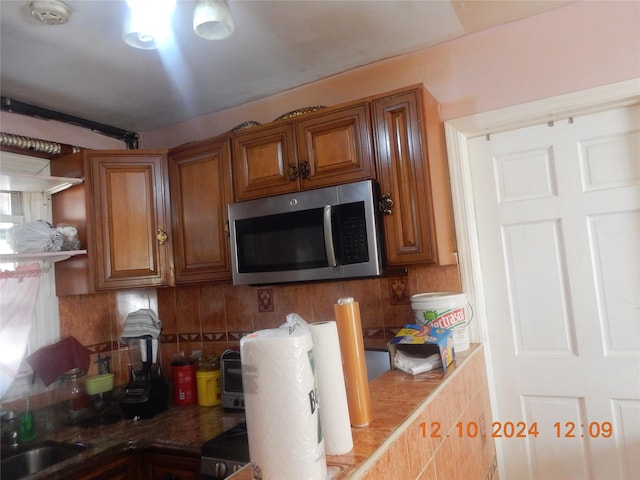 1027 E 83rd St E Unit 2, Brooklyn, NY 11236 - kitchen with stainless steel microwave, brown cabinetry, and backsplash