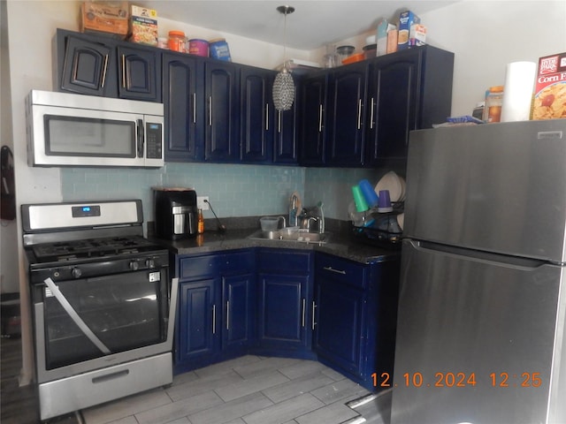 kitchen with blue cabinetry, backsplash, sink, and stainless steel appliances