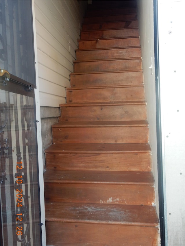 stairway featuring wood walls