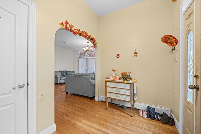 entryway with light hardwood / wood-style floors, baseboard heating, and a notable chandelier