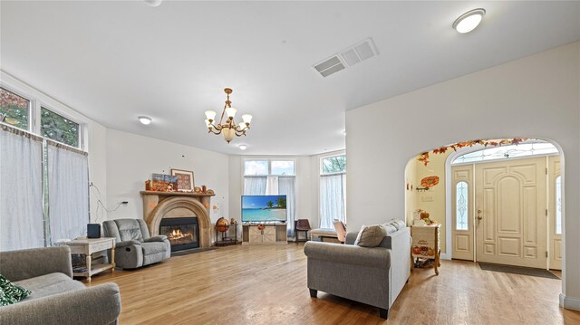 living room with a notable chandelier, light wood-type flooring, and a wealth of natural light