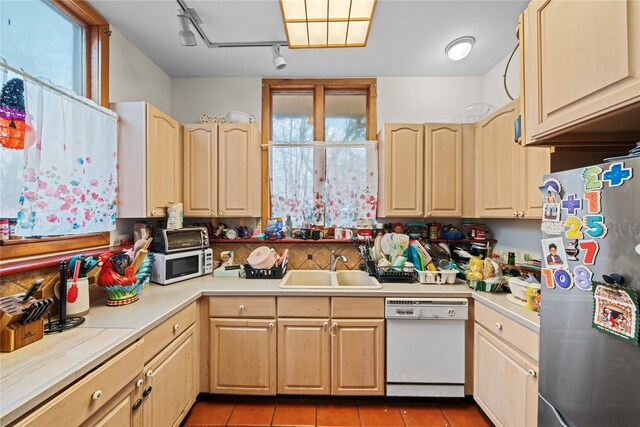 kitchen featuring white appliances, track lighting, sink, tile patterned flooring, and light brown cabinetry