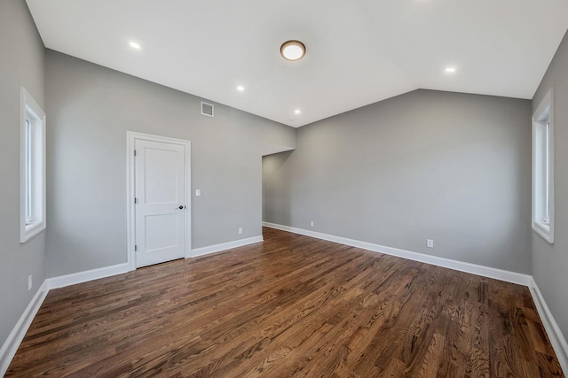 spare room with dark hardwood / wood-style floors and vaulted ceiling