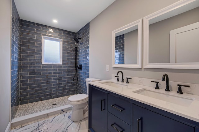 bathroom featuring a tile shower, vanity, and toilet