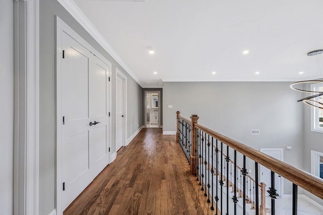 hallway featuring an inviting chandelier, crown molding, and dark wood-type flooring