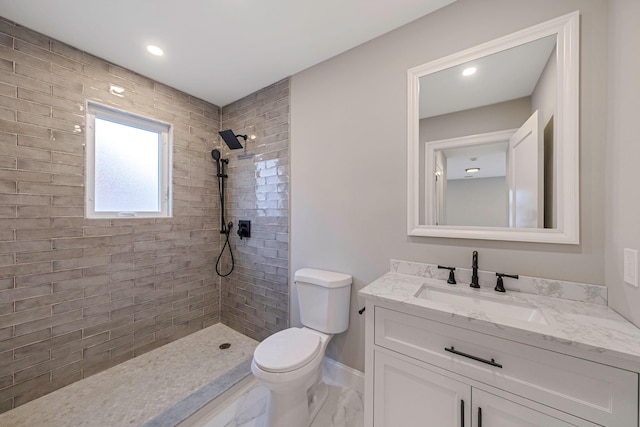 bathroom with vanity, toilet, and tiled shower