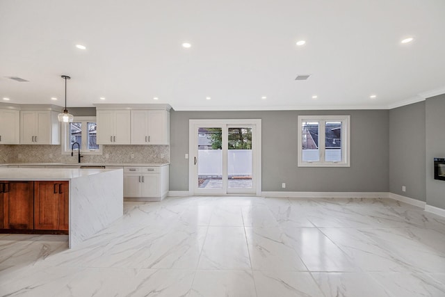 kitchen featuring white cabinets, sink, decorative backsplash, decorative light fixtures, and light stone counters