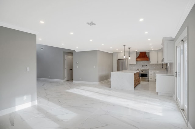 kitchen with decorative backsplash, stainless steel fridge, custom exhaust hood, a kitchen island, and hanging light fixtures