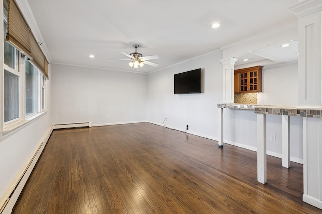 unfurnished living room with a baseboard heating unit, dark wood-type flooring, crown molding, and ornate columns