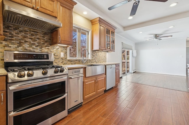 kitchen with under cabinet range hood, a sink, wood finished floors, range with two ovens, and dishwasher