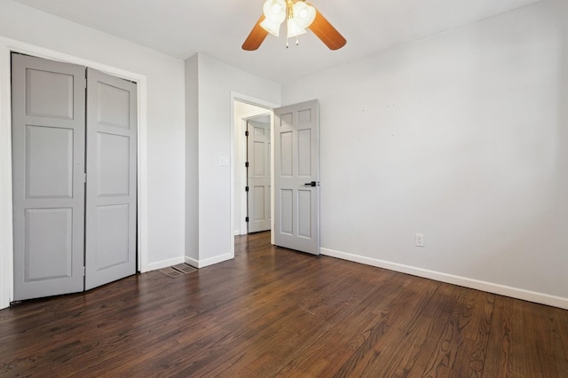 unfurnished bedroom with a closet, baseboards, dark wood-type flooring, and a ceiling fan