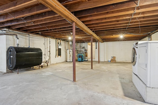 unfinished basement with water heater, a heating unit, washer / clothes dryer, and heating fuel