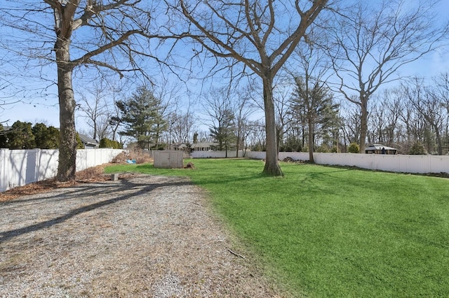 view of yard featuring an outbuilding, a storage shed, and a fenced backyard