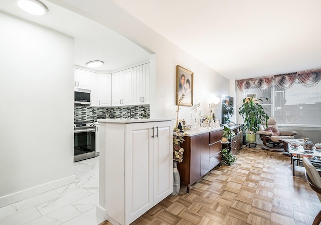 kitchen with appliances with stainless steel finishes, light parquet flooring, tasteful backsplash, and white cabinetry