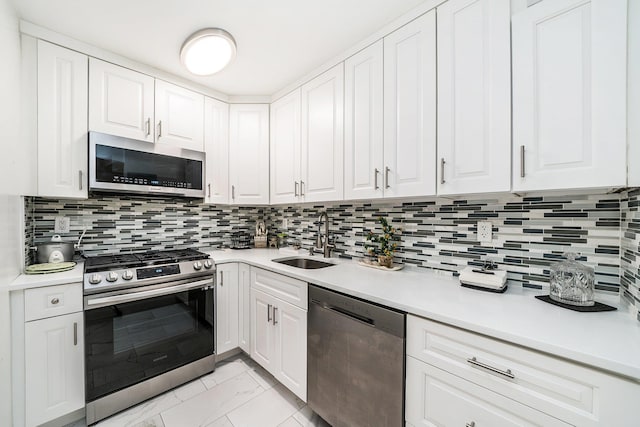 kitchen featuring decorative backsplash, stainless steel appliances, white cabinets, and sink