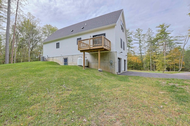 back of house featuring a garage, a deck, a yard, and central air condition unit