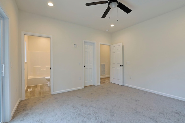 unfurnished bedroom with ceiling fan, light colored carpet, and ensuite bathroom