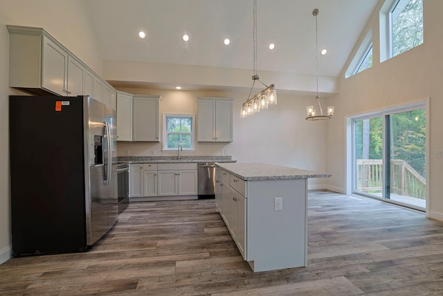 kitchen with sink, a center island, high vaulted ceiling, appliances with stainless steel finishes, and light wood-type flooring