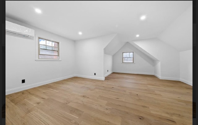 bonus room with vaulted ceiling, light hardwood / wood-style flooring, and a wall mounted air conditioner