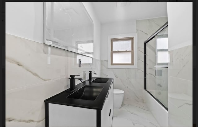 full bathroom with vanity, enclosed tub / shower combo, tile walls, and toilet