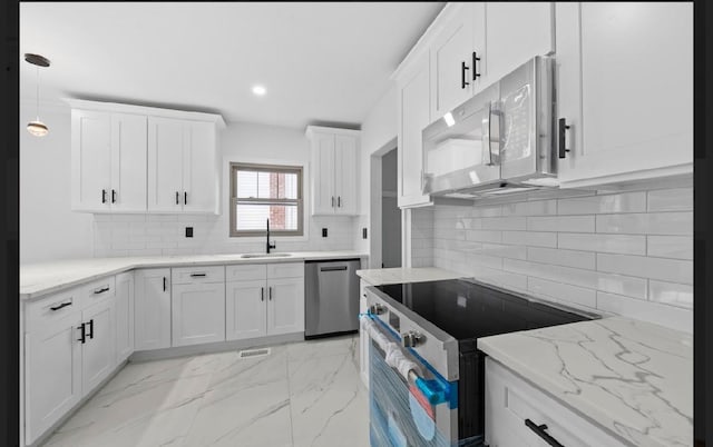 kitchen featuring stainless steel appliances, white cabinetry, hanging light fixtures, and sink