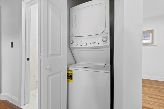 clothes washing area featuring light hardwood / wood-style floors and stacked washer / drying machine