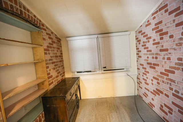 kitchen featuring dark brown cabinets, light colored carpet, and brick wall