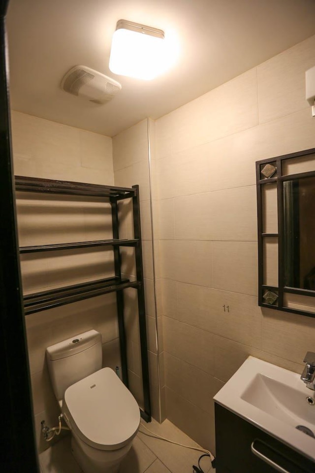 bathroom featuring tile patterned flooring, toilet, tile walls, and sink