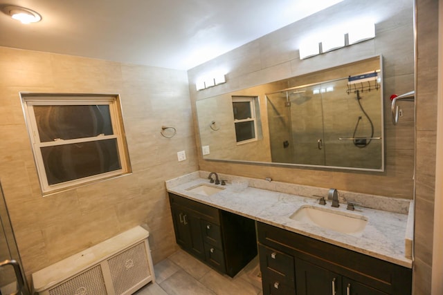 bathroom featuring radiator, tile patterned floors, a shower with door, vanity, and tile walls