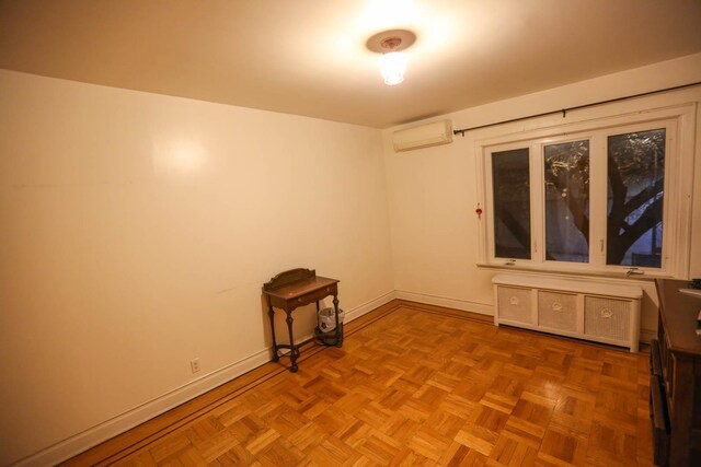 unfurnished room with a wall mounted air conditioner and light parquet flooring