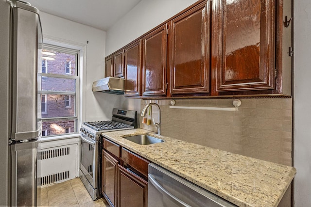 kitchen featuring appliances with stainless steel finishes, sink, light stone counters, and radiator heating unit