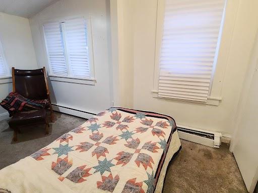 carpeted bedroom featuring baseboard heating and multiple windows