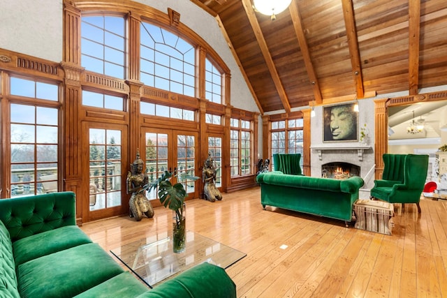 living room featuring a healthy amount of sunlight, light wood-type flooring, high vaulted ceiling, and french doors