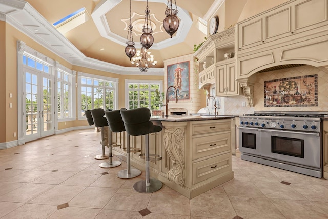 kitchen with tasteful backsplash, a breakfast bar, pendant lighting, range with two ovens, and cream cabinetry